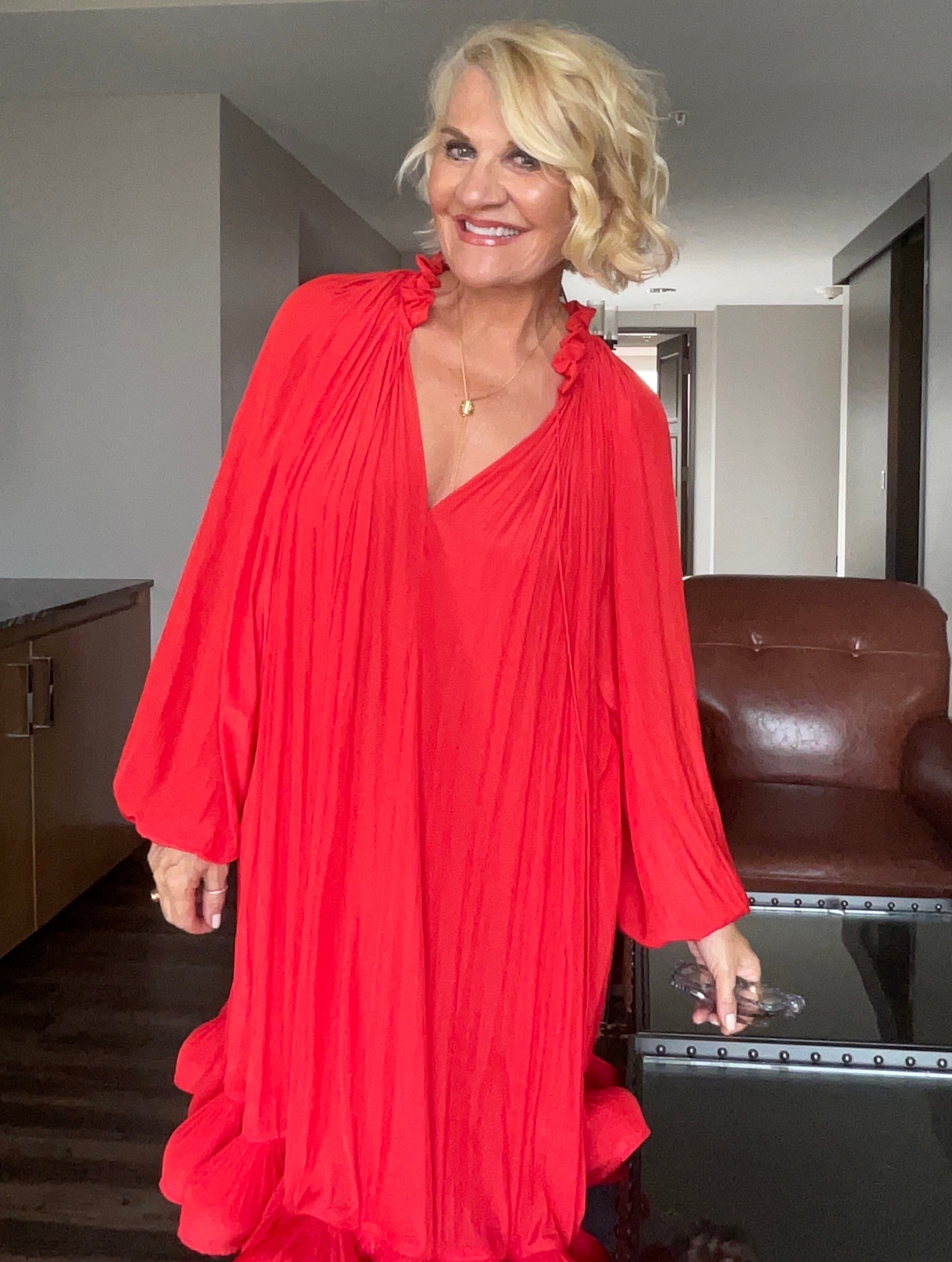 Global Fashion Expert Jacqui Stafford featured in a stylist red dress standing in her New York City apartment.